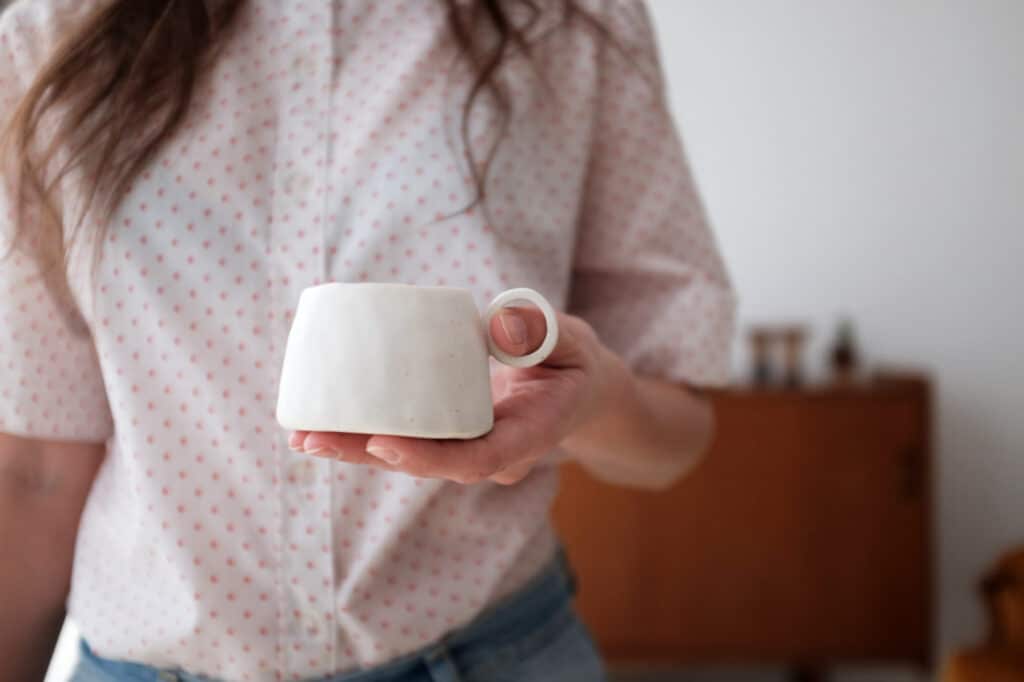 Femme tenant une tasse en céramique blanche faite main par Ici l’Atelier