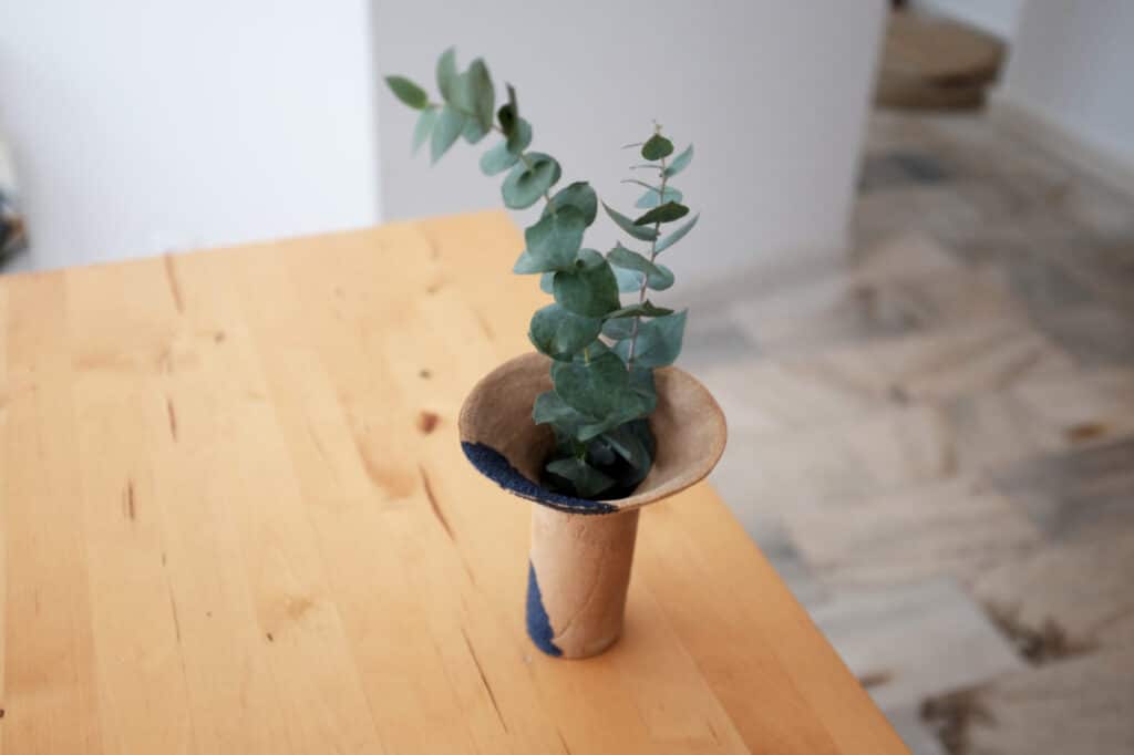 Petit vase en céramique avec une branche d’eucalyptus sur une table en bois