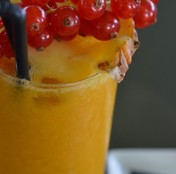Cocktail mangue-passion garni de groseilles en gros plan