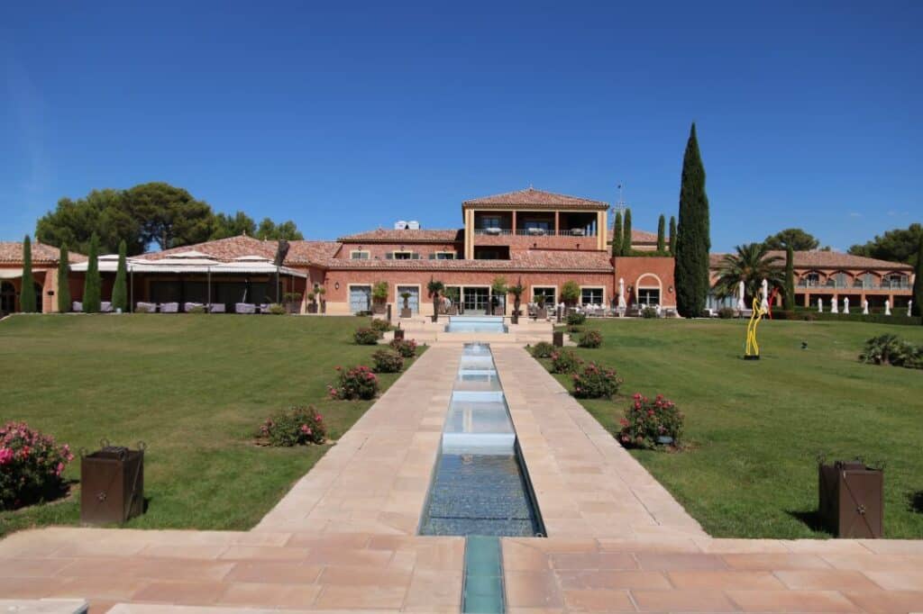 Bâtisse de l’Hôtel du Castellet et allée de bassins au milieu des pelouses