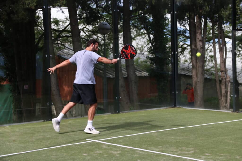 Joueur frappant une balle de padel sur un terrain synthétique vert