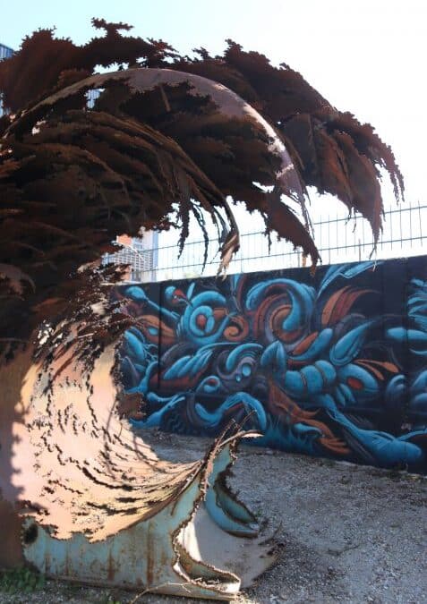 Sculpture en métal devant une fresque bleue aux Vivres de l’Art