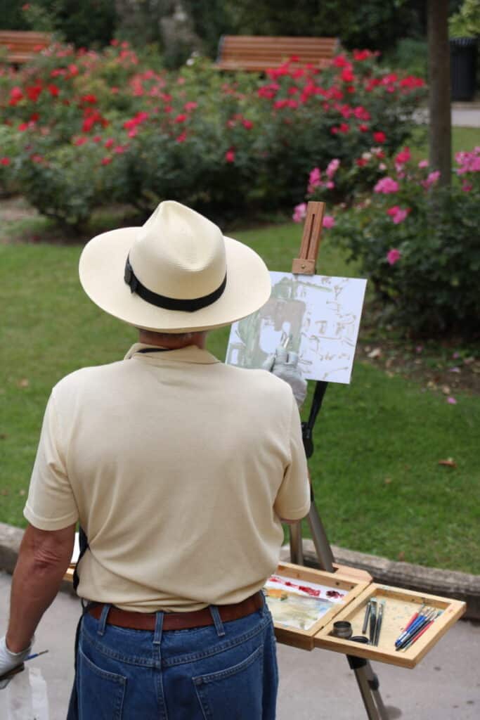 Peintre en chapeau devant son chevalet parmi les rosiers du Pavillon Vendôme