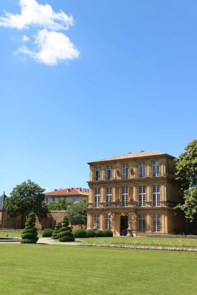 Façade du Pavillon Vendôme et jardin à la française sous un ciel bleu, à Aix-en-Provence