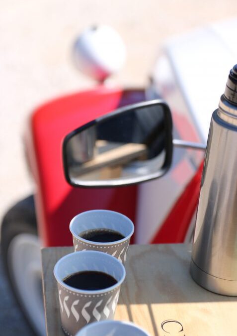 Gobelets de café et thermos posés sur la portière d’une 2CV rouge