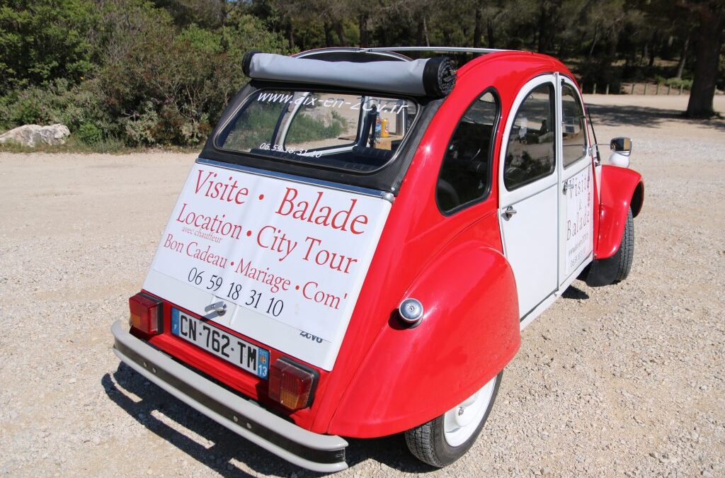 2CV rouge Aix en 2CV avec ses inscriptions publicitaires sur la capote