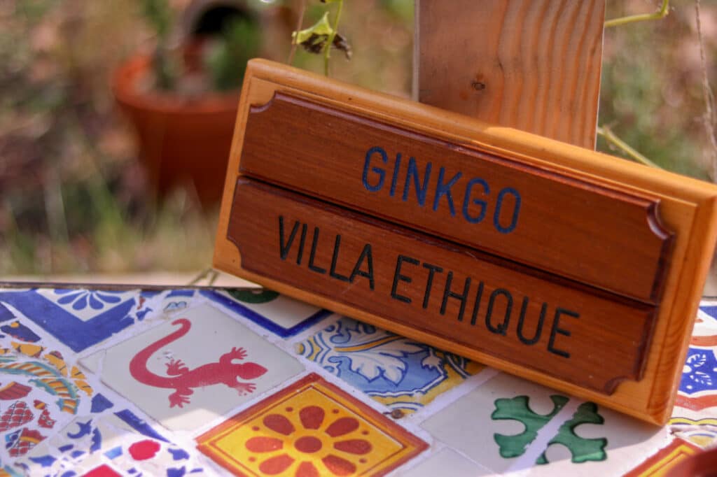 Pancarte en bois « Ginkgo Villa Éthique » sur une table en carreaux de ciment, à Marseille