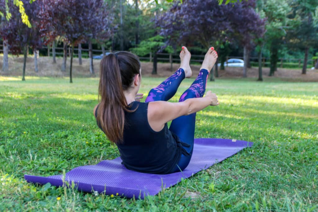 Femme faisant un exercice de yoga sur un tapis violet au parc de la Torse