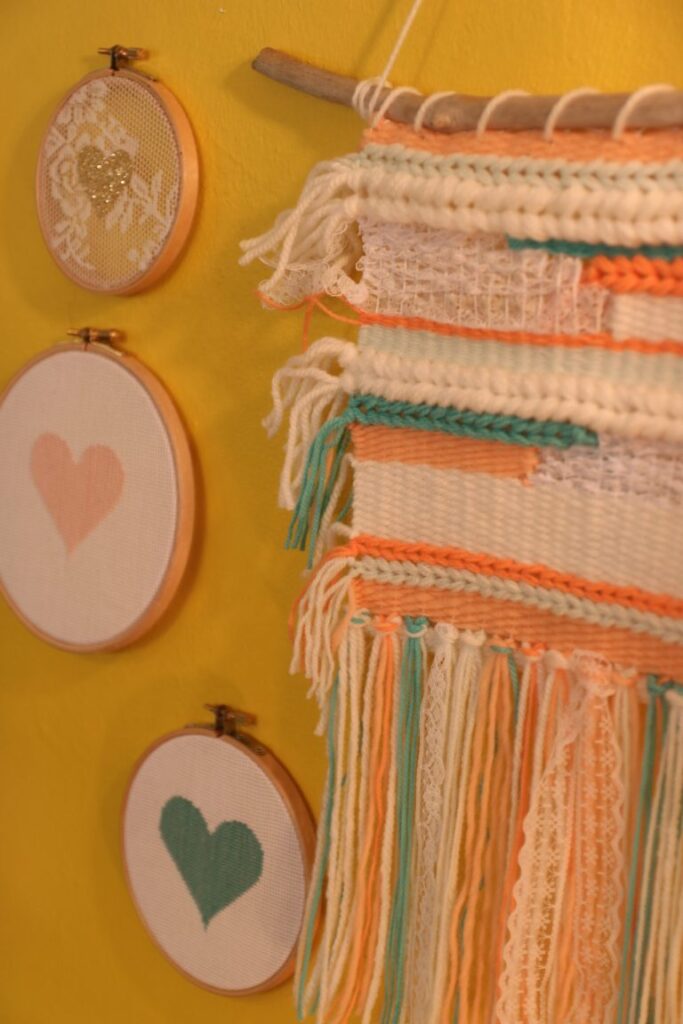 Tissage mural et broderies cœur sur un mur jaune au concept store Aix and Co