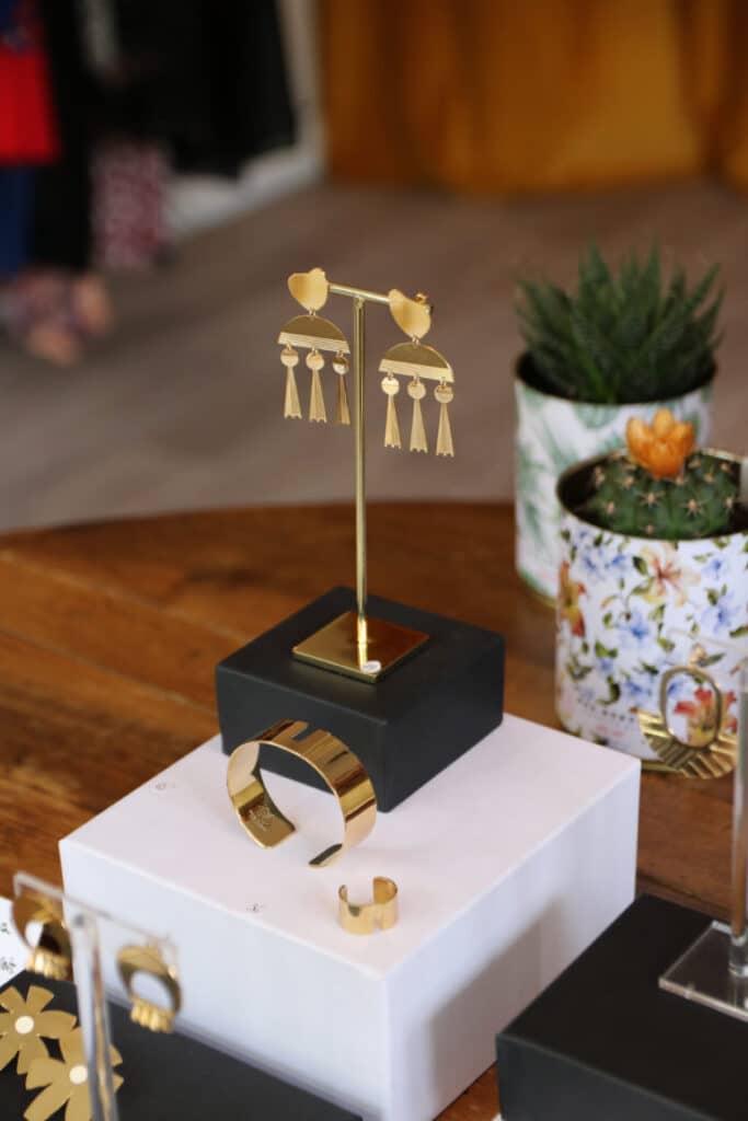 Boucles d’oreilles et bracelet dorés présentés sur un socle chez Abbie & Lou, à Salon-de-Provence