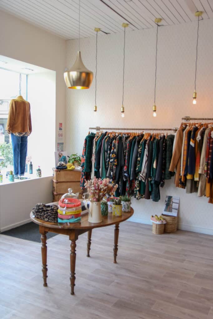 Intérieur lumineux de la boutique Abbie & Lou avec portants et table ancienne