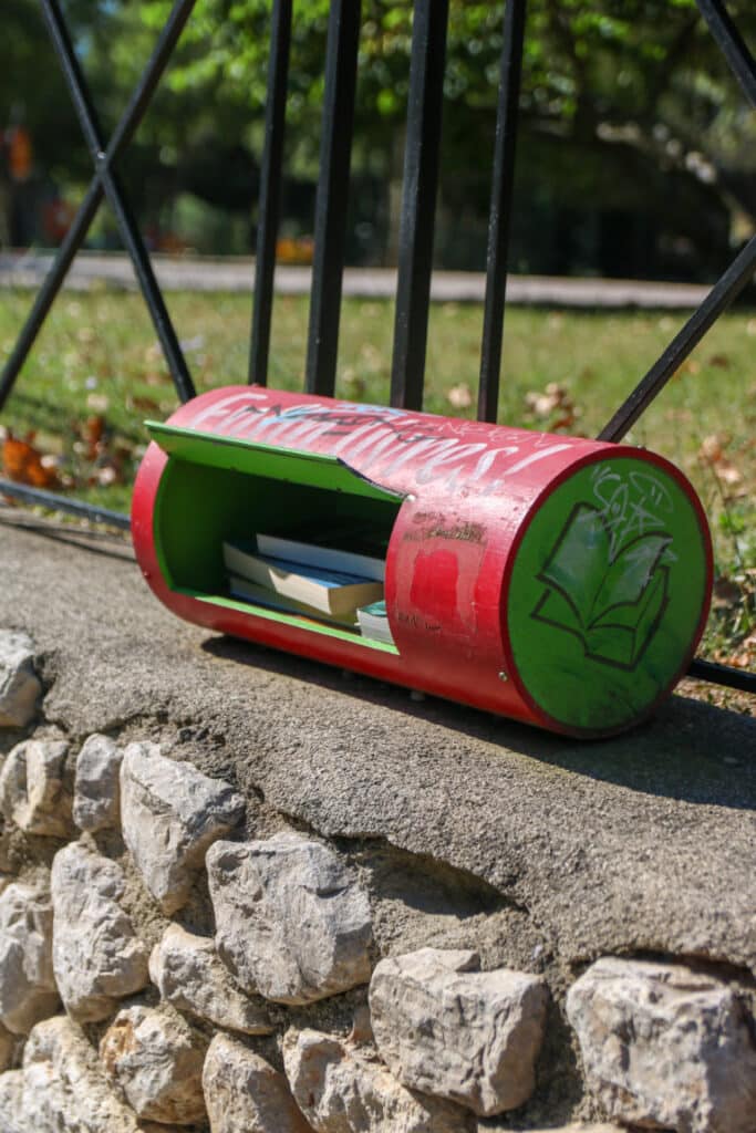 Boîte à livres rouge et verte posée sur un muret au parc Jourdan, à Aix-en-Provence