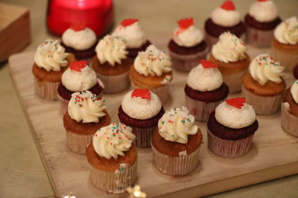 Cupcakes au glaçage blanc et décor rouge de Mary Cherry sur une planche en bois