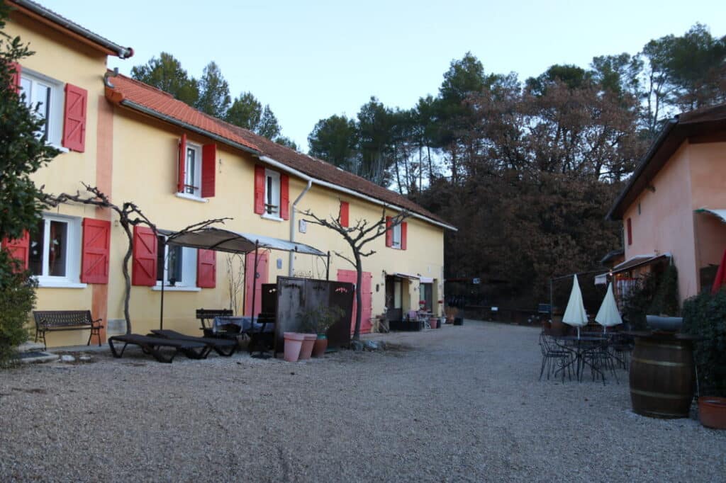 Bâtisse aux volets rouges et cour de l’Oustaou du Luberon