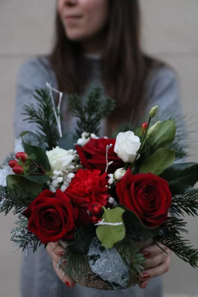 Femme tenant un bouquet de roses rouges et blanches réalisé à l’atelier floral de Villelaure