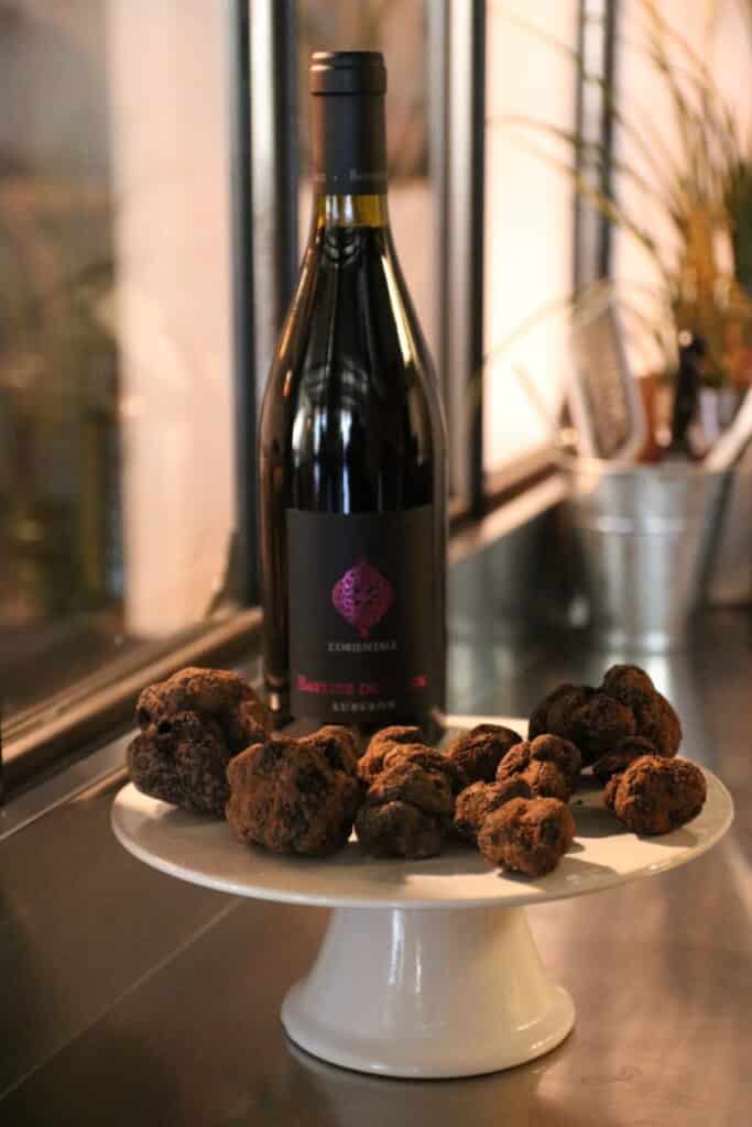 Bouteille de vin rouge et truffes noires sur un présentoir au Diamant Noir