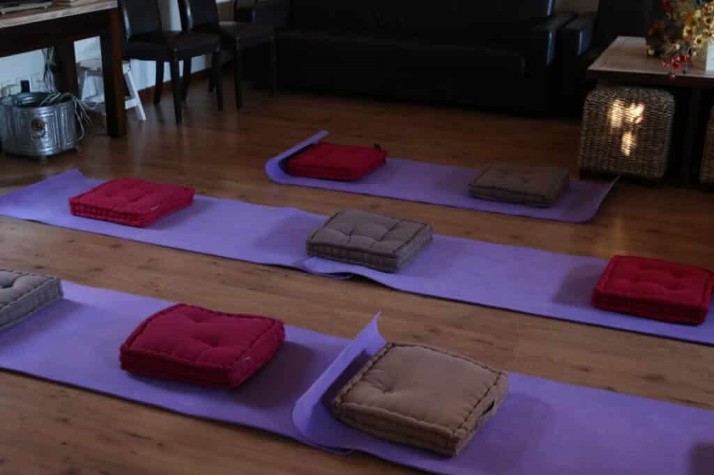 Tapis et coussins de méditation disposés au sol pour la séance de méditation guidée