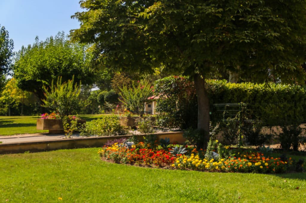 Pelouse, massifs fleuris et grands arbres dans un parc d’Aix-en-Provence