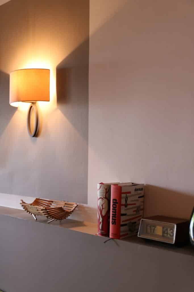Applique allumée et livres posés sur une console dans l’hôtel Victor