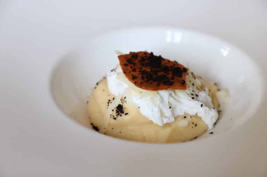 Œuf poché sur purée avec tuile croustillante dans une assiette blanche
