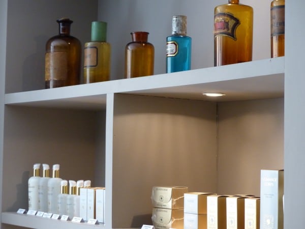 Étagères de flacons anciens et produits de soin à l’institut Les Petits Soins, à Aix-en-Provence