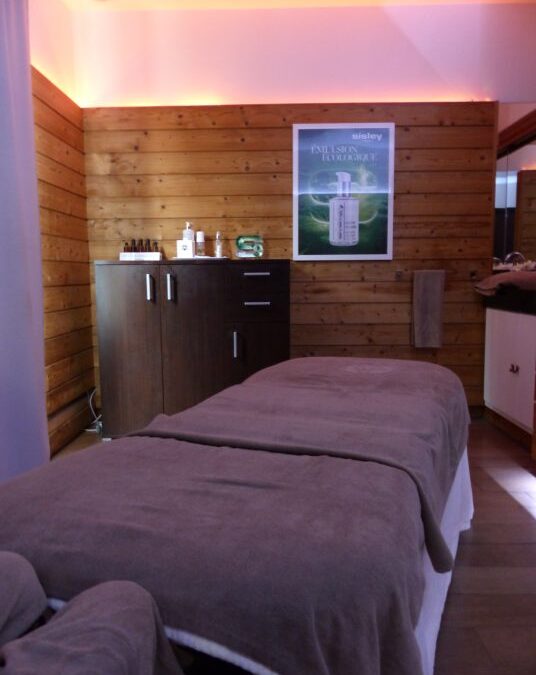 Cabine de soin aux murs en bois et table de massage au spa Baumanière