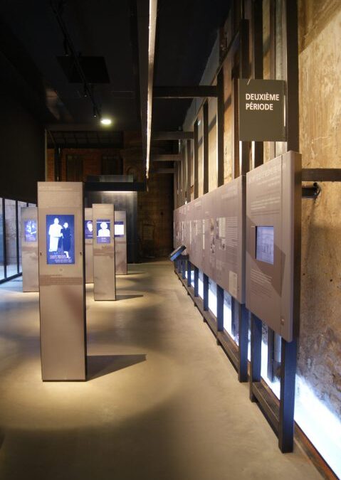 Couloir d’exposition aux vitrines éclairées du volet historique du Camp des Milles