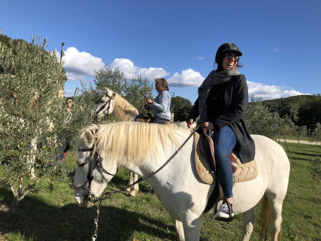 Cavalière sur un cheval blanc lors d’une balade avec La Ballade du Val de Cèze