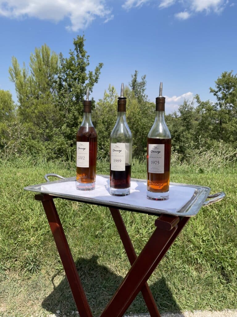 Trois bouteilles posées sur une table pliante dans les herbes à Villa La Coste
